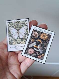 two small cards in the palm of someone's hand, one with a butterfly on it