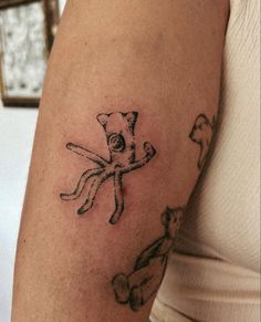 a woman's arm with an octopus and cat tattoo on the left side of her arm