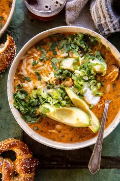 a white bowl filled with soup and topped with avocado, cilantro, bread