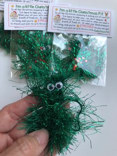 someone is holding up some fake grass with eyes on it and green tinsel in the background