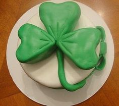 a white plate topped with a green cake covered in frosting and a four leaf clover