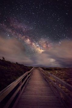 a wooden walkway leading to the stars in the sky