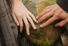 two people holding each other's hands on top of a rock