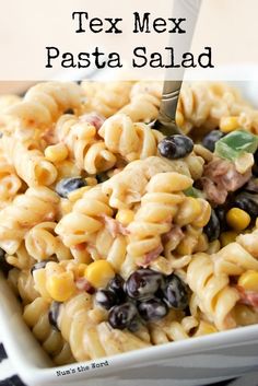 a white bowl filled with pasta and black olives next to a fork in it