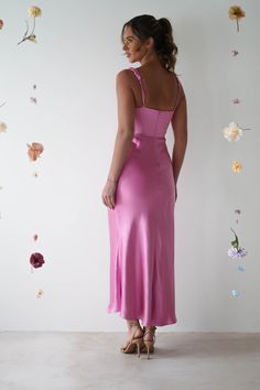 a woman in a pink dress is looking back at the wall with flowers on it