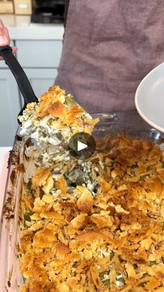 a person holding a spatula over a casserole dish