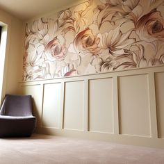 a chair sitting on top of a carpeted floor next to a wall with flowers painted on it