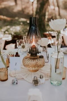 a table topped with vases and flowers on top of a white table cloth covered table