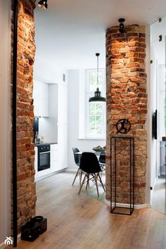 an open living room and dining area with brick walls, wood flooring and chairs