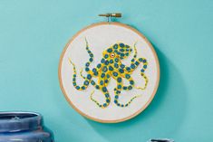 an embroidered octopus is hanging on the wall next to some vases and a potted plant