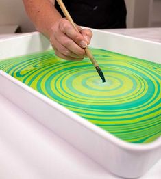 a person holding a paintbrush in a green and white tray