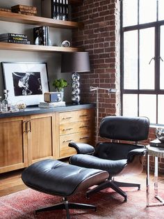 a living room with brick walls and wooden flooring, an eames chair in the foreground