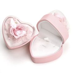 an open pink heart shaped box with a flower inside