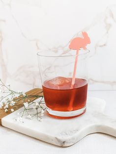 a drink in a glass with a pink straw sticking out of it on a marble tray