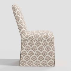 an upholstered chair with a beige and white pattern on the back, sitting in front of a gray background