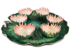 four pink water lilies sitting on top of a green leafy bowl with leaves