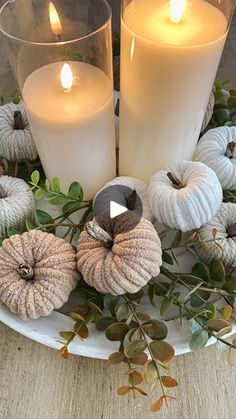 two candles are sitting on a plate with pumpkins