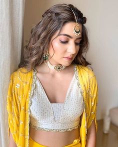 a woman in yellow and white outfit standing next to a window with her hands on her hips