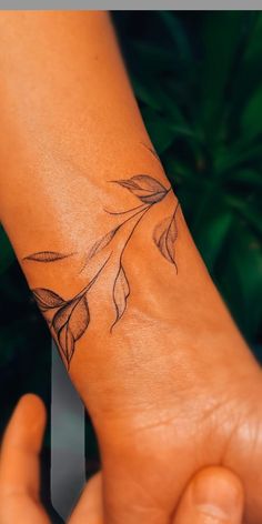 a woman's arm with a flower tattoo on the left side of her wrist