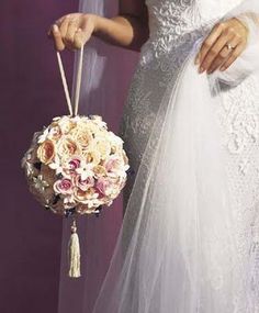 a woman in a wedding dress holding a bridal gown and bouquet with her hand