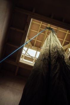 a large piece of cloth hanging from the ceiling in a room with wooden beams and windows