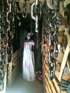 a person dressed as a ghost in a storage area with chains hanging from the ceiling