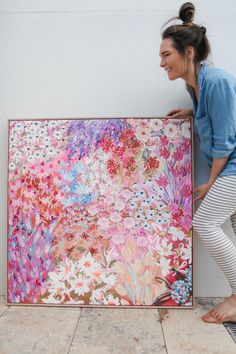 a woman standing next to a large painting