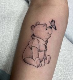 a small black and white tattoo of a bear with a butterfly on it's arm