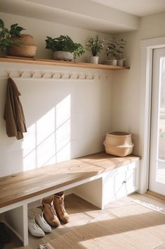 a wooden bench sitting under a window next to a pair of shoes and potted plants