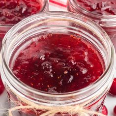 jars filled with cranberry sauce sitting on top of a table