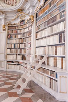 a white bench sitting in front of a bookshelf filled with lots of books