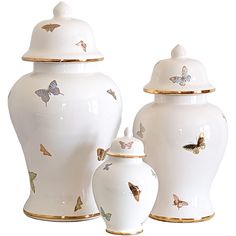 three white vases with gold trim and butterflies painted on the top, one has a lid