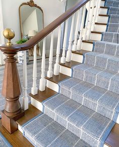 a staircase with blue and white carpeting next to a mirror on the wall above it