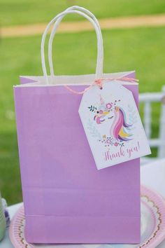 a purple bag with a unicorn on it sitting on top of a table next to a pink plate