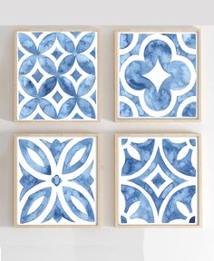 four blue and white wall art pieces hanging on the wall