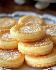 a white plate topped with lots of cookies covered in powdered sugar