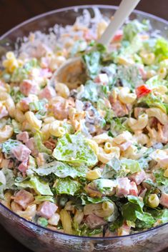 a bowl filled with pasta salad on top of a wooden table