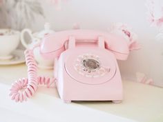 a pink phone sitting on top of a counter next to a cup and saucer