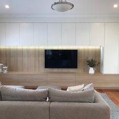 a living room with couches and a flat screen tv mounted on the back wall