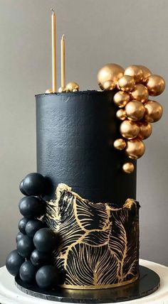 a black and gold cake with grapes on top