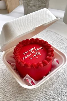 a red heart shaped cake in a white box on a table with an open lid