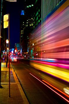 a city street filled with lots of traffic and tall buildings lit up by colorful lights