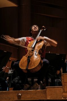 a man is playing an instrument in front of other people on the stage with their hands out