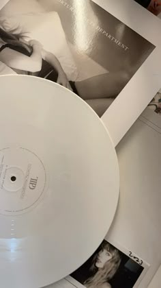 a white record player sitting on top of a table next to pictures and magazines with the cover pulled down