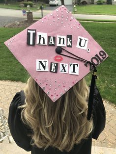 a person wearing a pink graduation cap with the words thank you next written on it