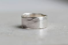 A chunky organic, rustic recycled silver ring with a hammered/textured finish. This unisex ring has an uneven finish and each one is truly unique. These make a lovely men's wedding band. The hammered finish gives the edge of the ring a 'wobbly' look which adds to it's character. The size measures approximately 8-9mm width x 1.2mm thickness. If you cannot see your size available then please get in touch as these rings can be made in any size. There is a thinner band version of this ring available Sterling Silver Rings Men, Male Rings Silver, Rustic Rings, Thick Ring, Men's Wedding Ring, Textured Ring, Unisex Ring, Recycled Silver, Metallic Foil