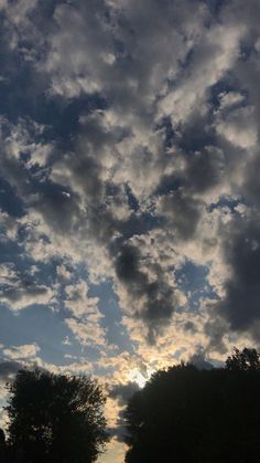 the sky is filled with clouds and trees