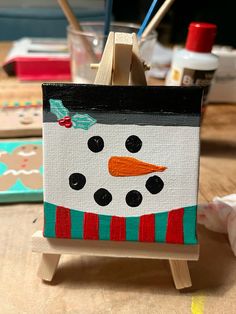 a snowman painted on an easel sitting on a table