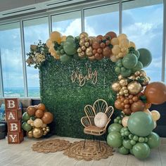 a backdrop with balloons and greenery for a baby shower