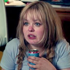 a young woman holding a can of soda in her hand and making a funny face